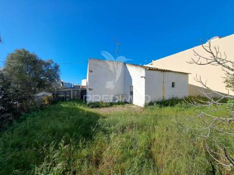 Terreno urbano com construção antiga no centro de quarteira